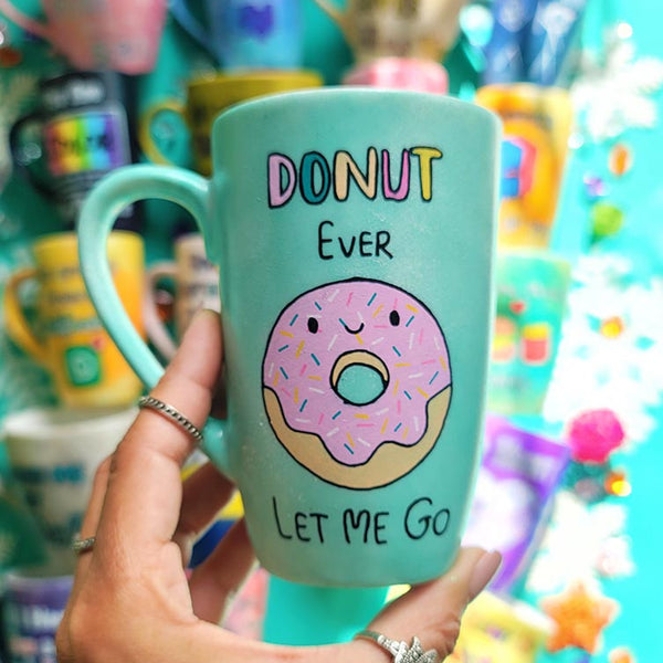 A Pastel green Hand-painted mug with the words "DONUT ever" and then below it a donut painted with pink frosting and sprinkles and a small smiley face. then below it the words "let me go"