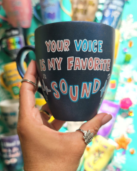 A shimmery blue hand painted mug with the sentence " your voice is my favorite sound" and sound beats painted on both sides