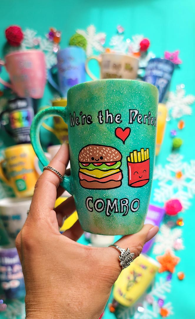 A hand-painted green galaxy mug with the words "we're the perfect combo"