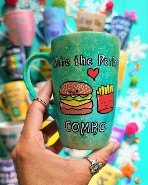 A hand-painted green galaxy mug with the words "we're the perfect combo"