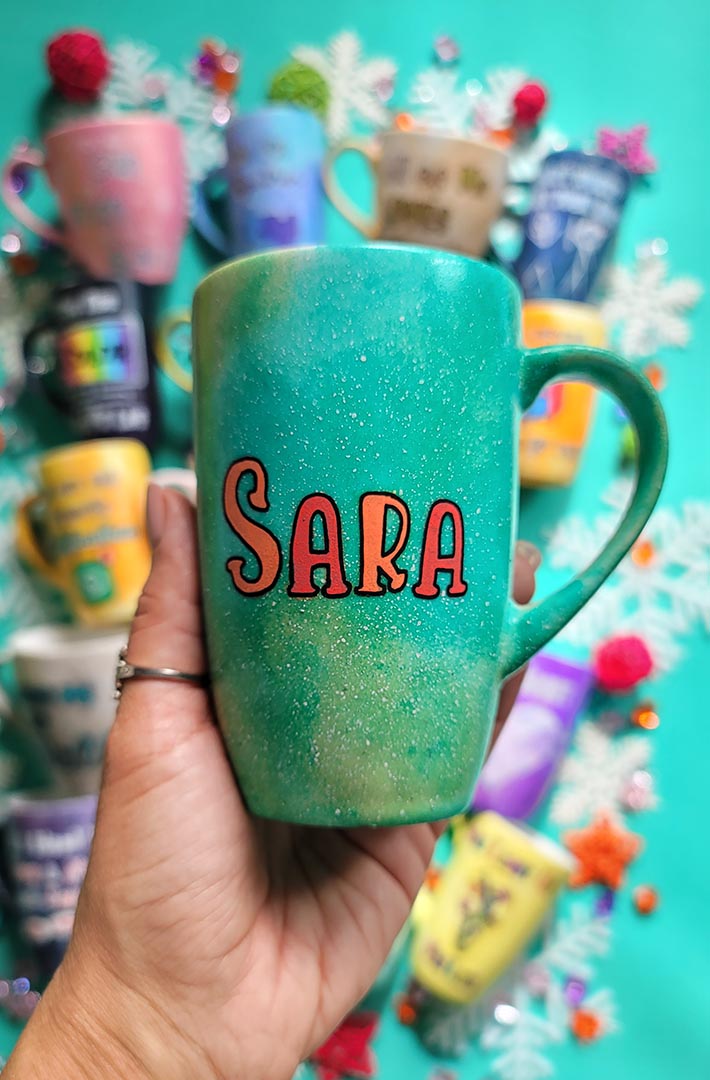 A hand-painted green galaxy mug with the name "Sara"