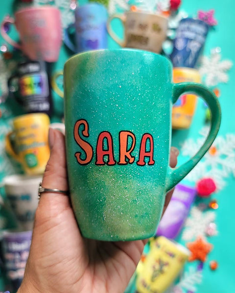 A hand-painted green galaxy mug with the name "Sara"