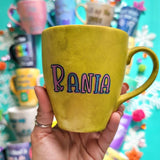 A hand-painted greenish bronze mug with the name 