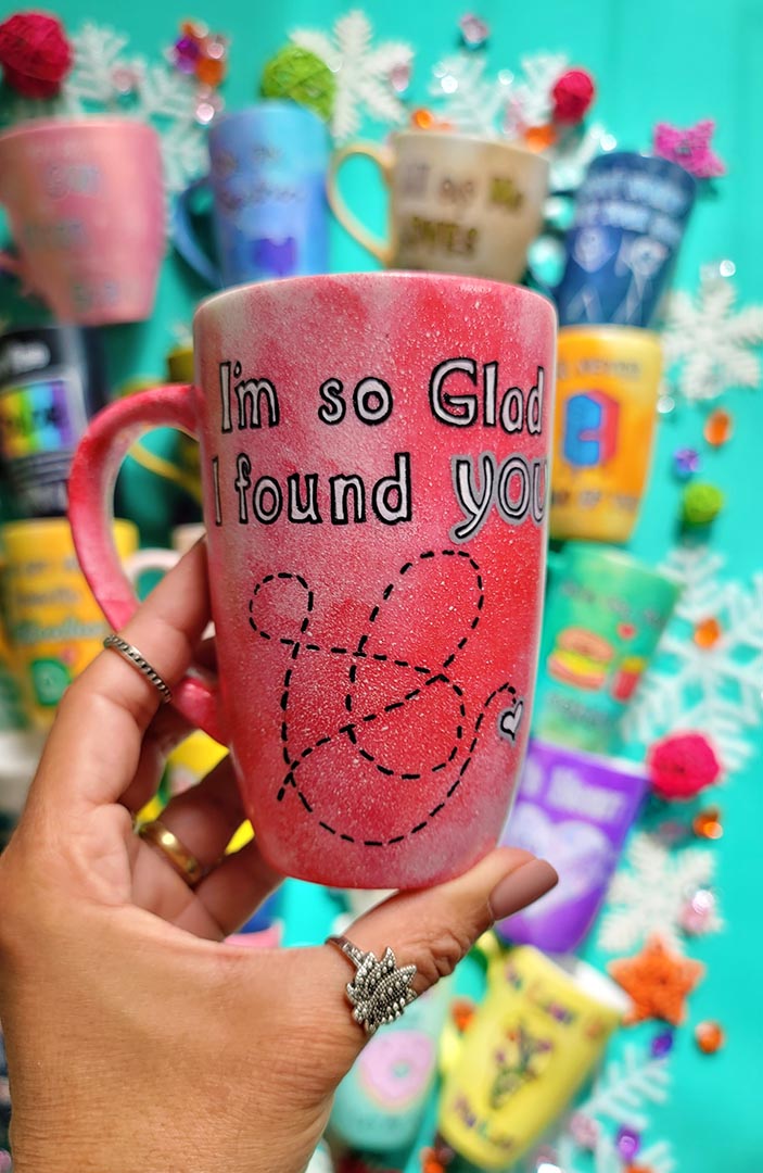 A hand-painted red galaxy mug with the words "I'm so glad I found you" and then a dotted line drawn like a path to reach a small heart in the bottom right corner