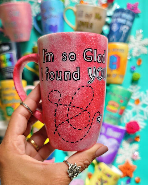 A hand-painted red galaxy mug with the words "I'm so glad I found you" and then a dotted line drawn like a path to reach a small heart in the bottom right corner