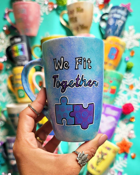 A hand-painted  light blue purple mug with the words "we fit together" and then below it a painting of two puzzle pieces perfectly fitting together