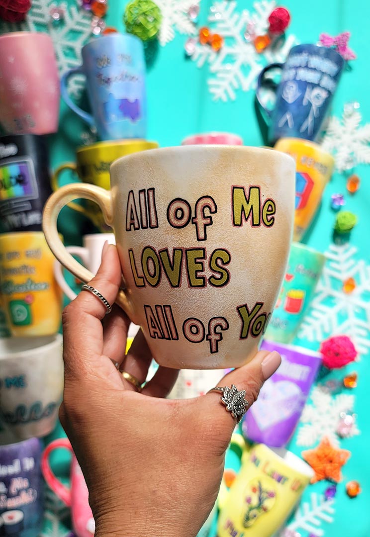 A hand-painted goldish mug with the words "all of me"