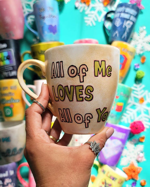 A hand-painted goldish mug with the words "all of me"