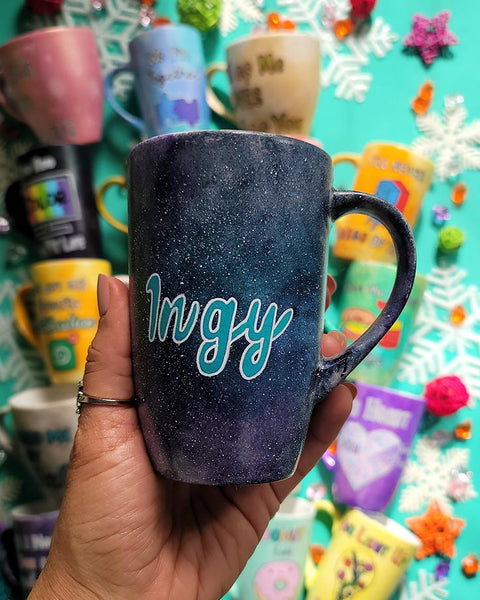 A hand painted black galaxy mug with the name "ingy"