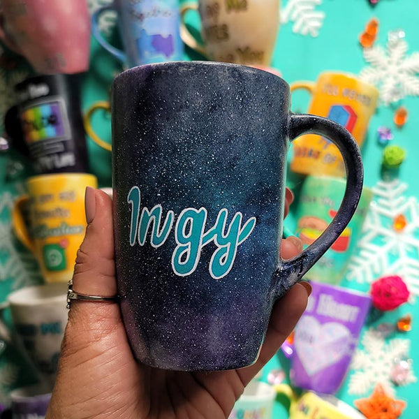 A hand painted black galaxy mug with the name "ingy"