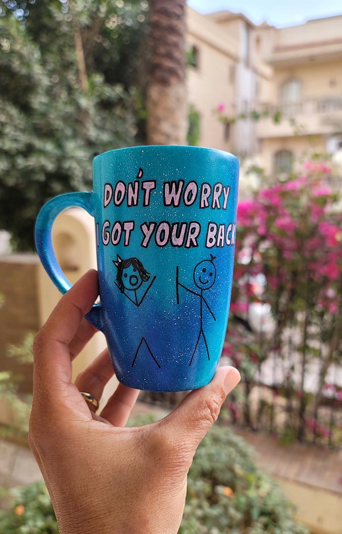 A hand painted blue galaxy mug with the words "dont worry, I got your back " and a drawing of 2 stick figures with the boy holding the back of the girl