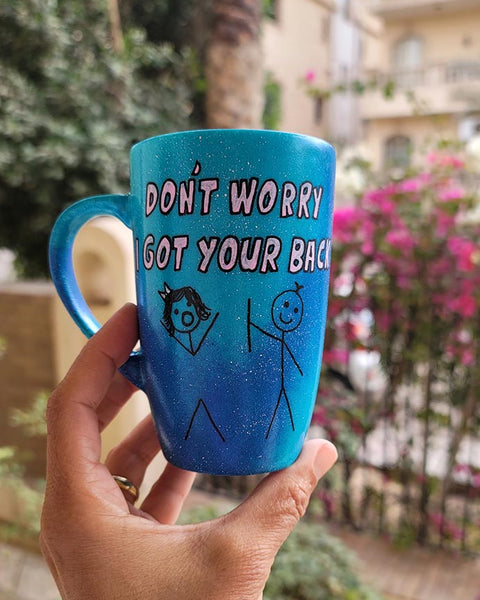 A hand painted blue galaxy mug with the words "dont worry, I got your back " and a drawing of 2 stick figures with the boy holding the back of the girl