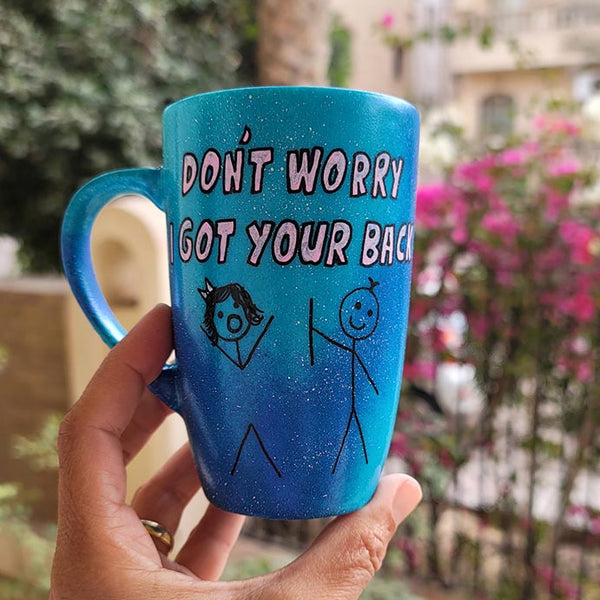 A hand painted blue galaxy mug with the words "dont worry, I got your back " and a drawing of 2 stick figures with the boy holding the back of the girl