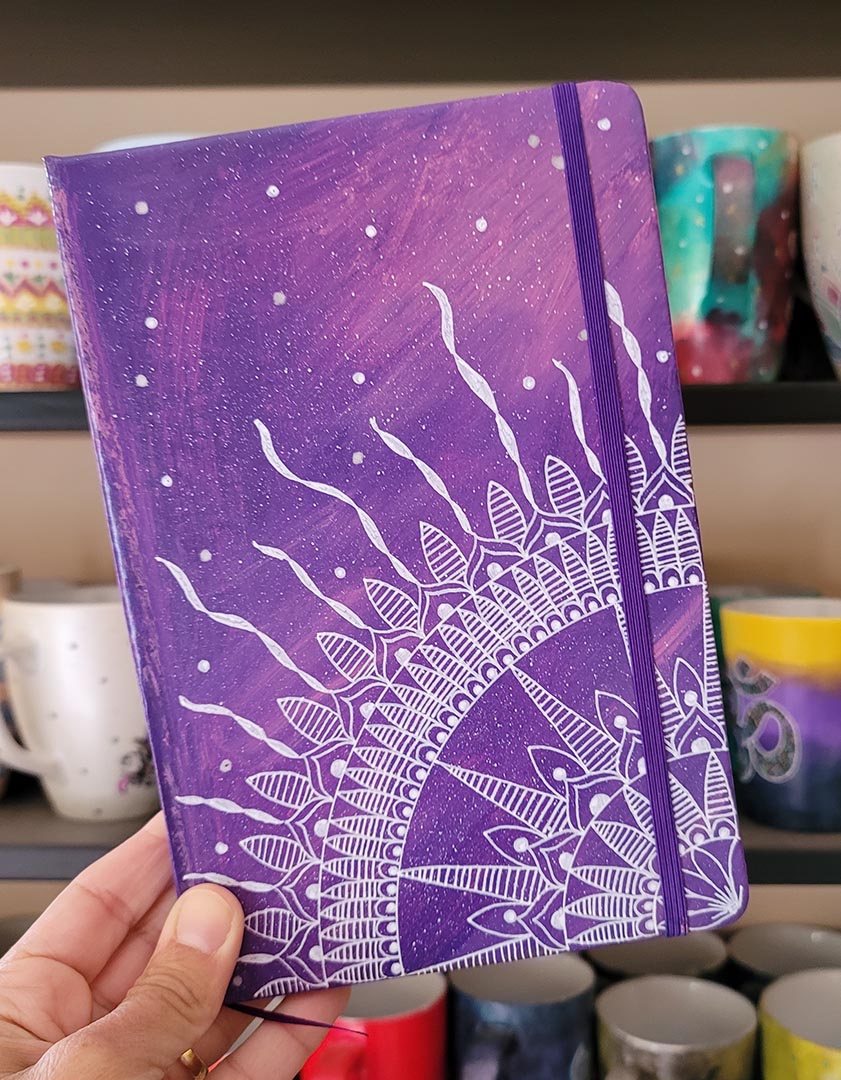 A Purple Galaxy hand painted notebook with a quarter mandala drawn from the corner