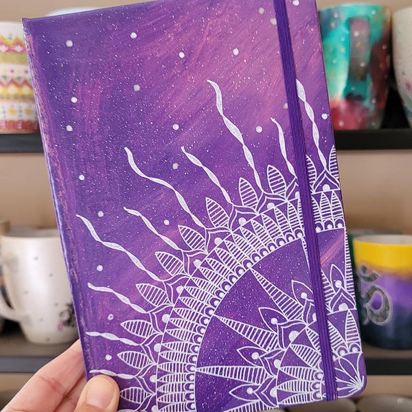 A Purple Galaxy hand painted notebook with a quarter mandala drawn from the corner