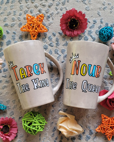 2 hand-painted taupe mugs, one with the words "Tarek the king" and the other with the words "Nour the queen"