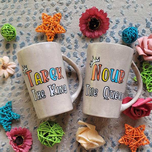 2 hand-painted taupe mugs, one with the words "Tarek the king" and the other with the words "Nour the queen"