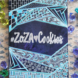 A Bluish galaxy hand painted notebook with patterns on the top and bottom and the words 