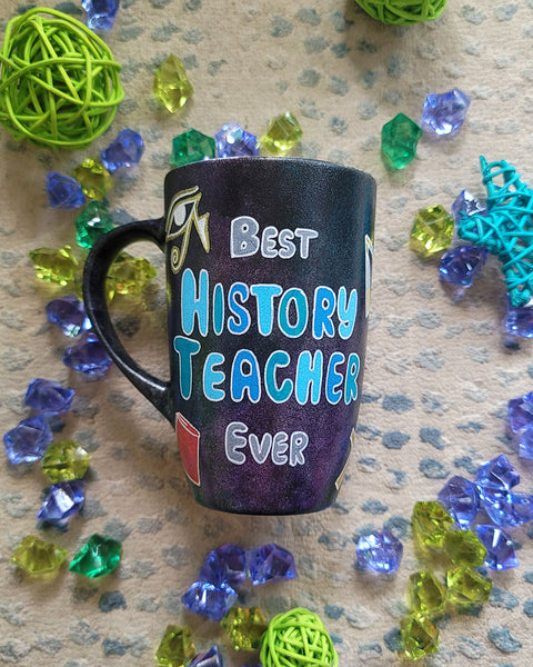 A Black Sky Hand painted mug with the words "Best History teacher Ever" and Egyptian history icons scattered all over