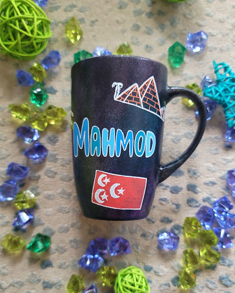 A Black Sky Hand painted mug with the name "Mahmod" and Egyptian history icons scattered all over