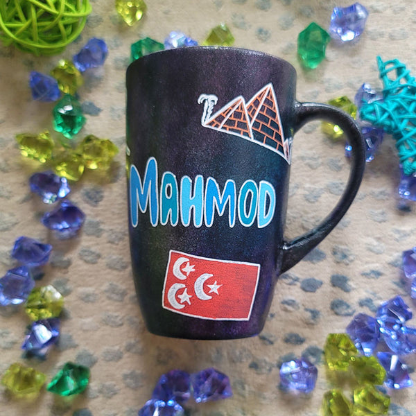 A Black Sky Hand painted mug with the name "Mahmod" and Egyptian history icons scattered all over