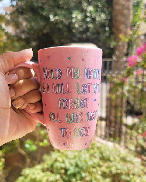 A hand-painted shimmery pink mug with the words "Hold my hand and I will Let you forget all who lied to you"