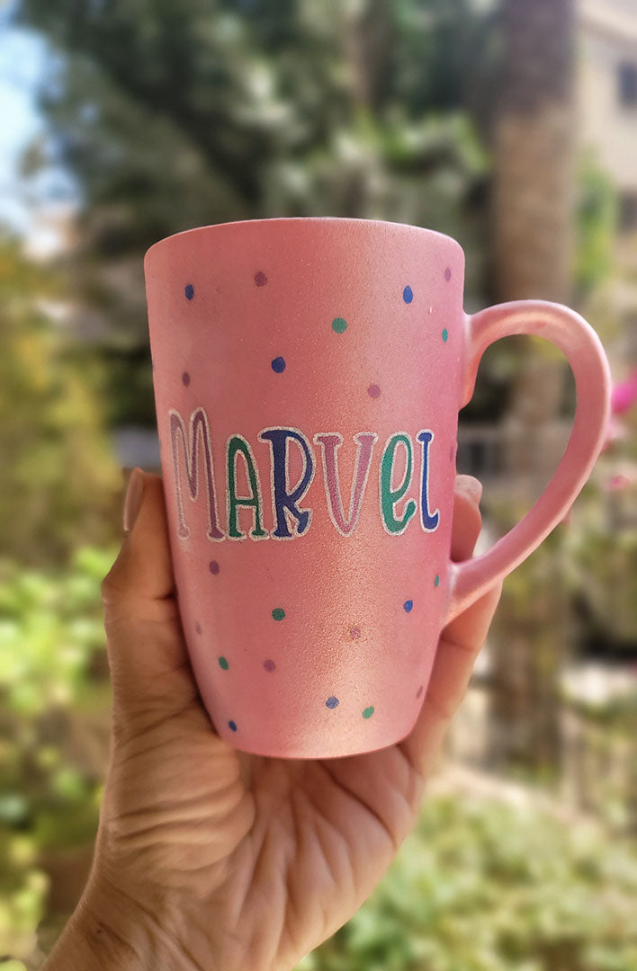 A hand-painted shimmery pink mug with the name "Marvel" 