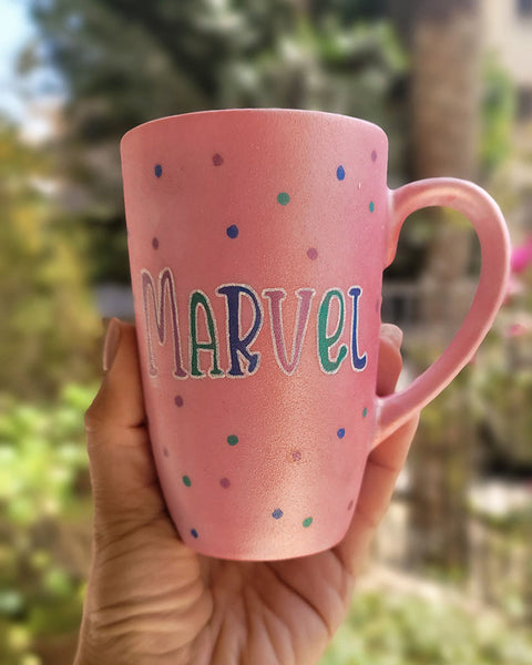 A hand-painted shimmery pink mug with the name "Marvel" 