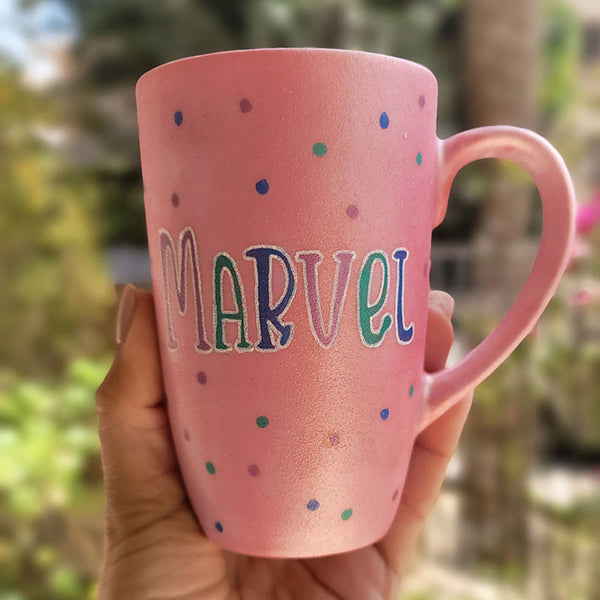 A hand-painted shimmery pink mug with the name "Marvel" 