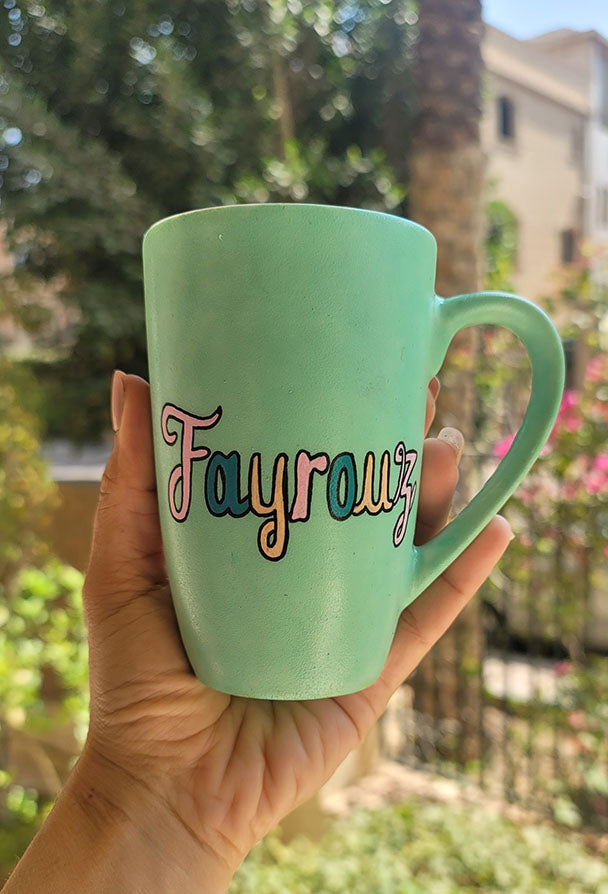 A Hand painted green Mug with the name "Fayrouz" written