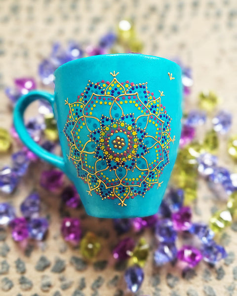 A hand painted blue Indian color mug with a mandala painted in gold