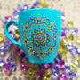 A hand painted blue Indian color mug with a mandala painted in gold