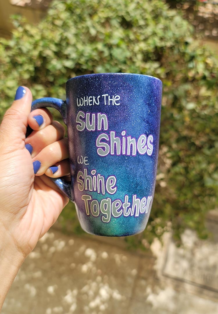 A Black Galaxy hand painted mug with the sentence "when the Sun shines, we shine together"