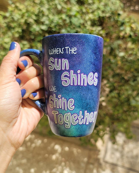 A Black Galaxy hand painted mug with the sentence "when the Sun shines, we shine together"