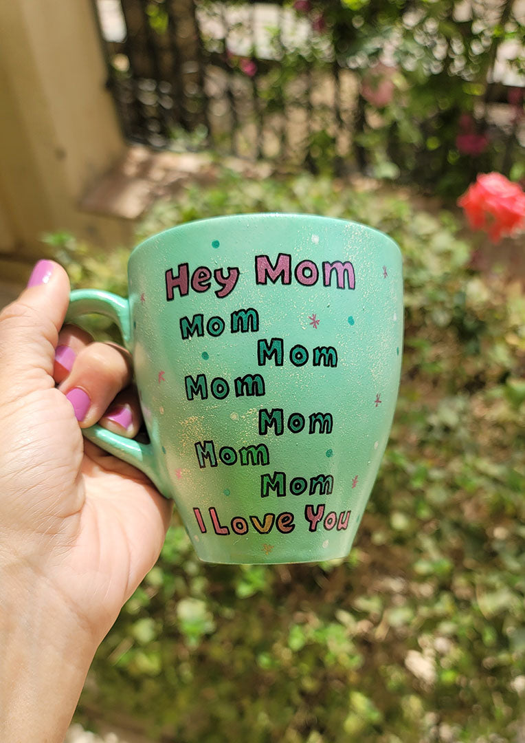 A mint Colored mug with the sentence "Hey mom mom mom mom mom mom I love you" with white and green dots and pink stars scattered all over