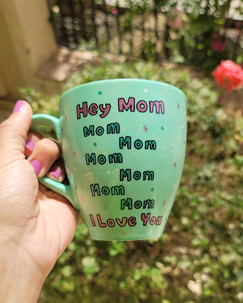 A mint Colored mug with the sentence "Hey mom mom mom mom mom mom I love you" with white and green dots and pink stars scattered all over