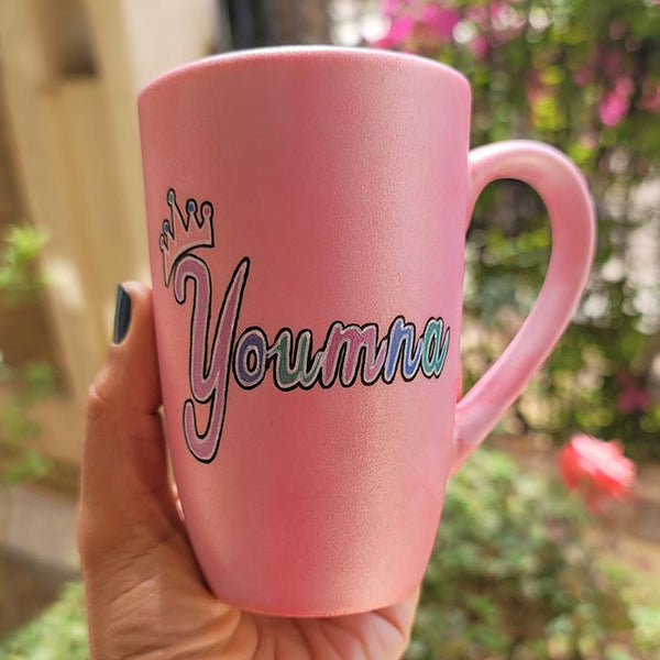 A shimmery pink hand-painted mug with the word miss crossed out and the name "Youmna" and a little crown on the letter Y