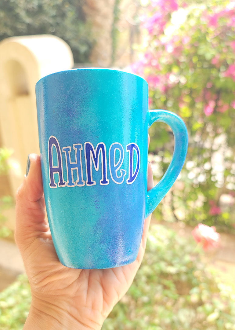 A blue hand painted mug with the name "Ahmed"