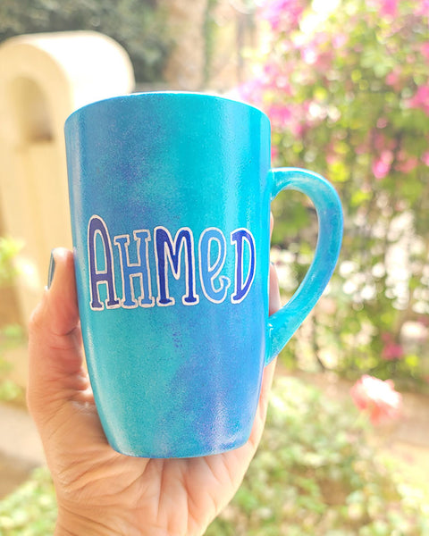 A blue hand painted mug with the name "Ahmed"