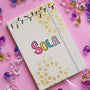 A white notebook with geometric patterns in gold in the background and festive lights all over the top, with the name "Sola" written in the center