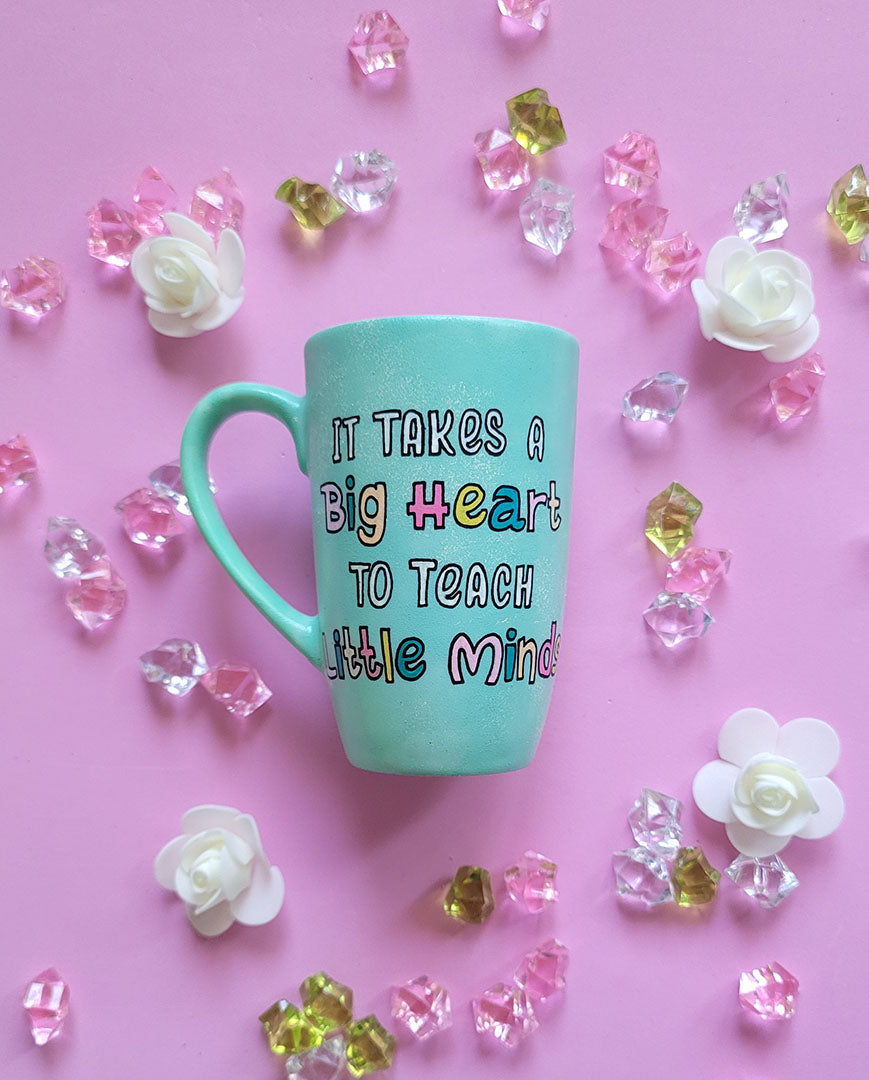 A Mint green handpainted mug with the words "its takes a big heart to teach little minds"