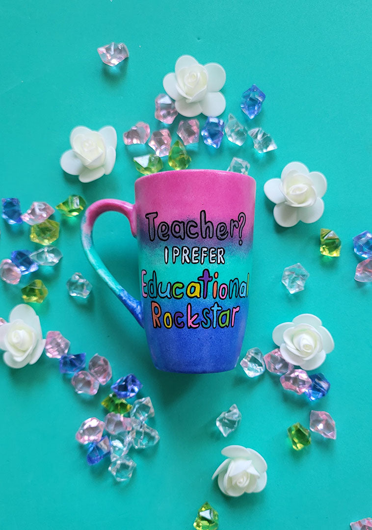 A Gradient hand painted mug (Pink Green and ultramarine) with the sentence "Teacher? I prefer Educational Rockstar"