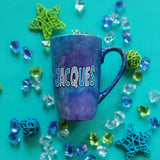 A bluish galaxy hand painted mug with the name 