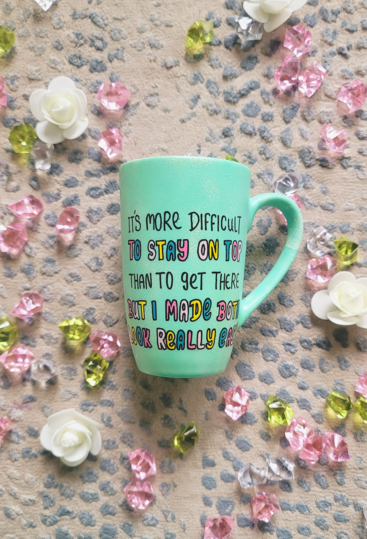 A Mint hand painted mug with the sentence "It's more difficult , to stay on top , than to get there. But I made Both look really easy"