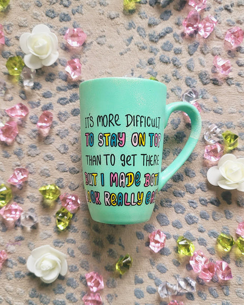 A Mint hand painted mug with the sentence "It's more difficult , to stay on top , than to get there. But I made Both look really easy"