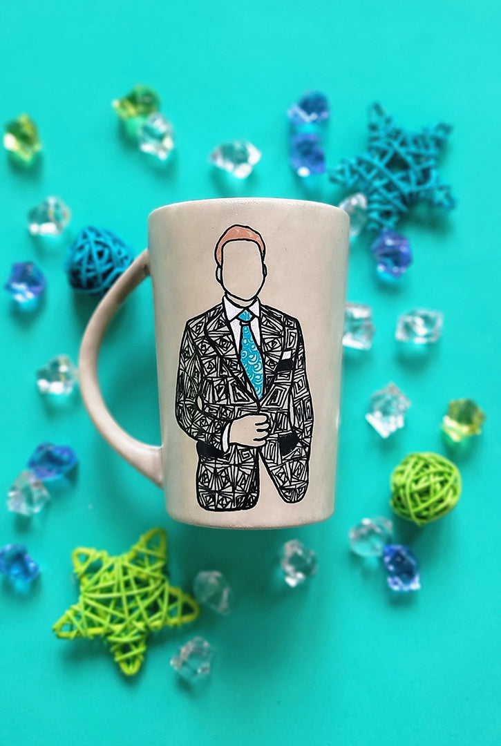 A taupe hand painted mug with a silhouette of a man in a suit filled with patterns