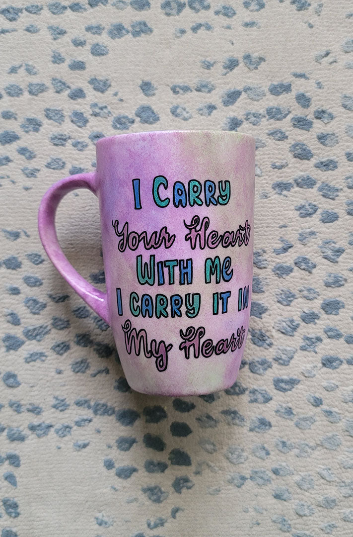 A Pastel Pink hand painted mug with the sentence" I Carry your heart with me, I carry it in my Heart"