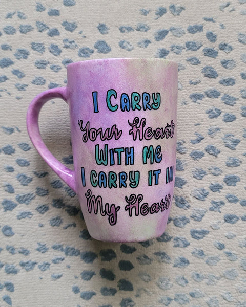 A Pastel Pink hand painted mug with the sentence" I Carry your heart with me, I carry it in my Heart"