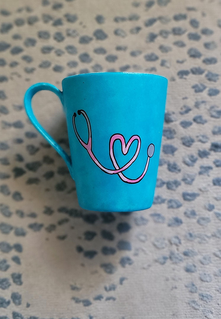 A Light blue mug with a stethoscope painted in pink