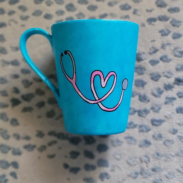 A Light blue mug with a stethoscope painted in pink